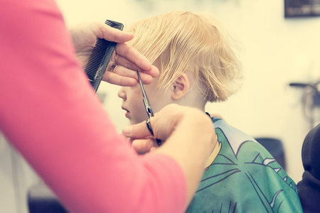 Cute blonde girl having her first haircut.