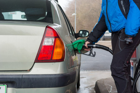 Detail view of hand holding fuel nozzle at petrol station.
