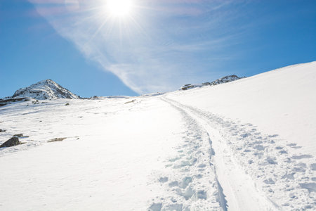 Spectacular winter mountain view with ski trail ascending a slope.