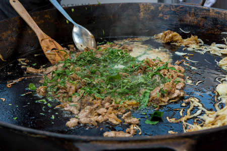 Cheff cooking delicious liver and onion dish in a large pan.の写真素材