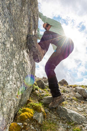 Female mountaineer practicing boulder climbing outdoor on large boulder.の写真素材