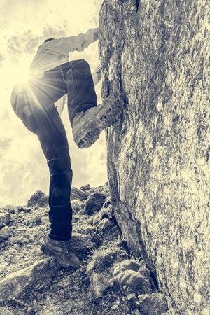 Female mountaineer practicing boulder climbing outdoor on large boulder. Active sport in the nature.
