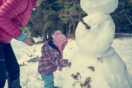 Mother and daughter building a snow man.