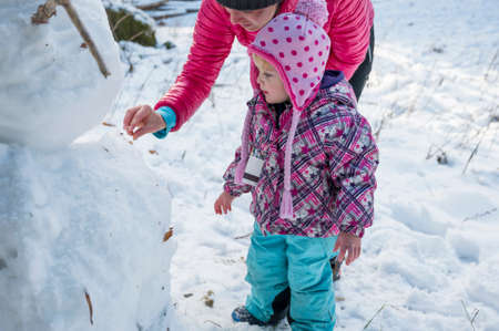 Mother and daughter building a snow man.の写真素材