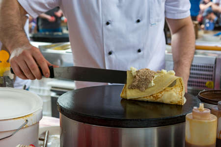 Cheff preparing tasty pancake with wallnuts and cream. Open kitchen event, Ljubljana.の写真素材