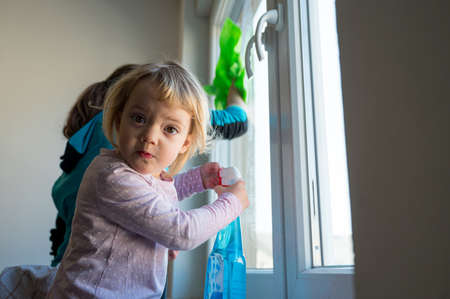 Cute girl helping mother to clean windows.の写真素材