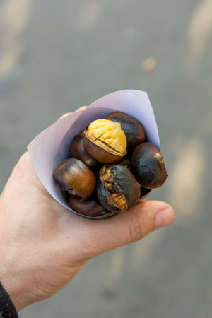 Drop down view of hand holding cone with delicious chestnuts.