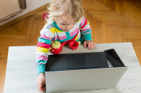 Cute blonde girl having a drink while working on a computer.