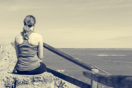 Active woman sitting and enjoying sea view. Living life and meditating.