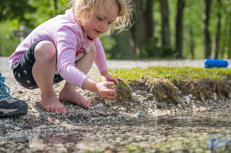 Young girl playing with stones in lake.の写真素材
