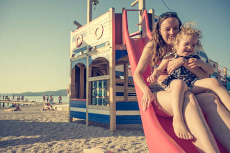 Mother and daughter riding a slide at the beach.の写真素材