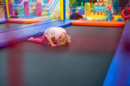 Cute blonde girl having fun at outdoor trampolin.の写真素材