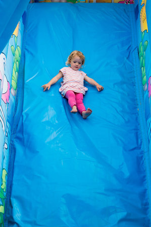 Cute blonde girl riding an inflatable slide.