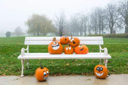 Many pumpinks with painted faces on white porch.の写真素材