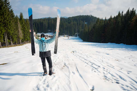 Female skier posing with a pait of skis wearing protective face mask.の写真素材