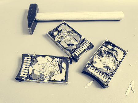 Three hard disk drives with shattered platter on a table.
