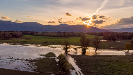Spectacular aerial panorama of river flowing through fields at sunset.の写真素材