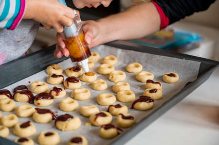 Cute blonde girl making cookies with her mother.の写真素材