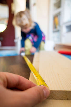 Detail of child helping with measuring wooden plank to make shelves.の写真素材