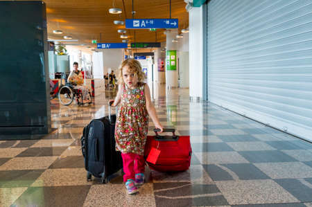 Cute blonde girl with travel luggage at the airport.の写真素材