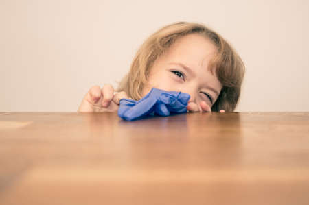 Portrait of cute blonde girl putting on robber gloves at home.の写真素材