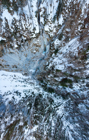 Spectacular drop down view of waterfall falling over rocky forest ledge.