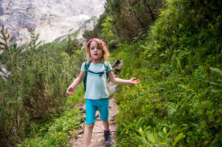 Cute girl walking along mountain trail descending into forest.の写真素材