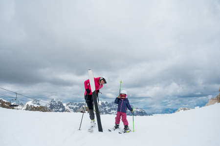 Mother and daughter having fun and learning skiing making first steps on a ski winter resort at mountain hill.の写真素材
