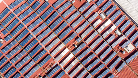 Drop down view of solar power plant with panels placed on industrial roof tops.