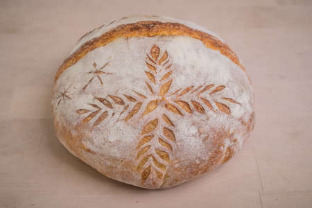 Home made traditional loaf of bread in slovenia with carved images of leaves and grain wheat on the crust. Festive bread with ornamental decorations.の写真素材