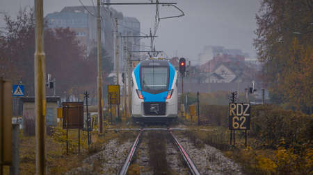 Modern white and blue passenger commuter train passing by in rain. Rainy commute with a modern train in cold and grey weather.の写真素材
