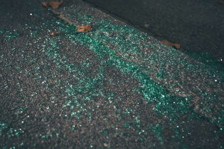 Pieces of broken green tinted car glass as a leftover from a burglary. Remains of a car burglary, pieces of glass on the road or sidewalk.の写真素材