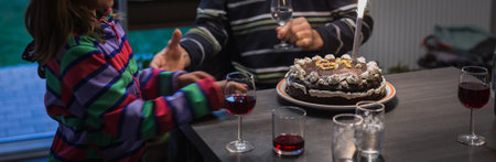 Horizontal panorama picture of a home made cake for birthday of an elderly person, with kid congratulating.の写真素材