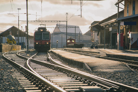 Train station in switzerland, frontal view of the train and train tracks in strong evening sunset...
