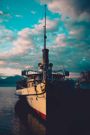 Front view of old steamboat from early 20 century moored in the port of Ouchy in Lausanne, Switzerland on an early sunny winter morning with some clouds above it.の写真素材