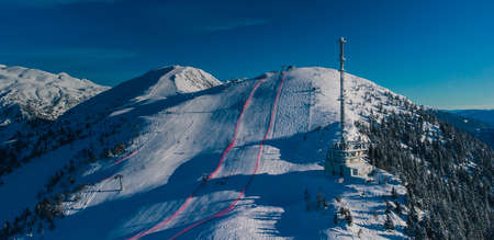 Aerial panorama of ski slope of Krvavec in Slovenia, visible TV tower or antenna and also a ski race course between the red fence.の写真素材