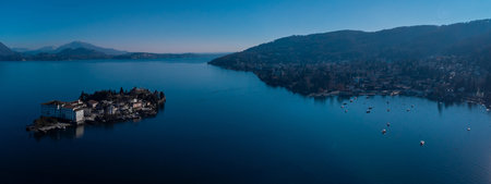 Wide aerial panorama of Isola Bella on lago Maggiora in italy on a beautiful sunny winter day. Fancy tourist city of Stressa is seen on far right.の写真素材