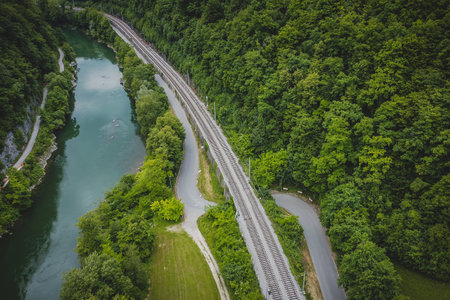 Panorama of tight river valley with cramped railway line and road next to a wide green Sava river...
