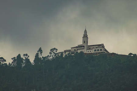 Panoramic view of Montserrat church on top of the hill in Bogota, Colombia on a cloudy hazy day. Mysterious photo of a church above Bogota.の写真素材