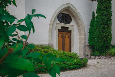 Entrance of a gothic medieval church surrounded by green leaves and bushes Fairytale wooden entrance into a church.の写真素材