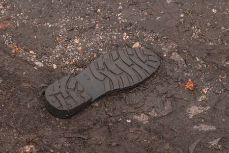 Underside of a shoe tread visible that it fell off and is now stuck in the mud.の写真素材