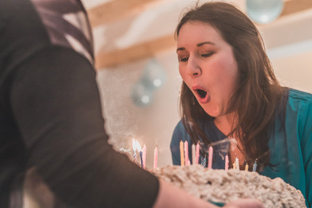 Young caucasian brunette woman blowing out candles on a birthday cake with candles. Tasty birthday...