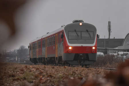 Old commuter diesel train approaching the station on a cloudy day.の写真素材