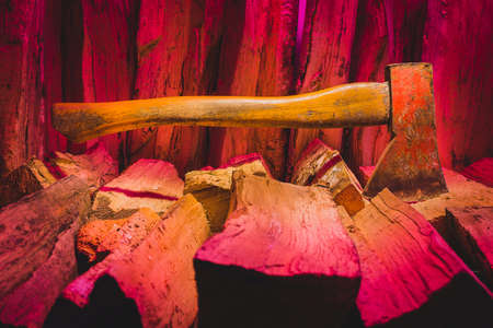Hatchet axe and a pile of split wood logs used for fire. Concept with purple colors of the bacground. Axe viewed from the side.の写真素材
