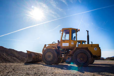 A tractor excavator in the sun. Yellow machine waiting for next duties.の写真素材