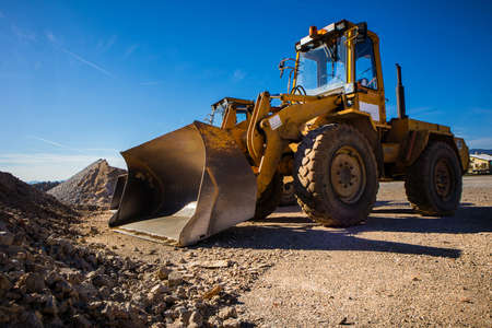 A tractor excavator in the sun. Yellow machine waiting for next duties.の写真素材