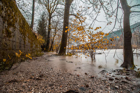 Flooded path in autumn, due to high river waters because of the rain. Dull gray day.の写真素材