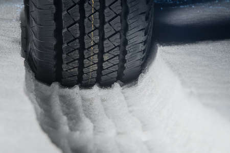 All terrain tire in snow. Snow track visible in snow with a rubber car or SUV tire in front. Tread marks in snow. Winter road safety concept.の写真素材