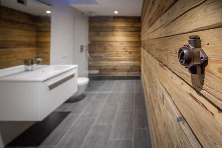 An old electrical switch in a modern bathroom with wooden walls and grey tiles on the floor.の写真素材