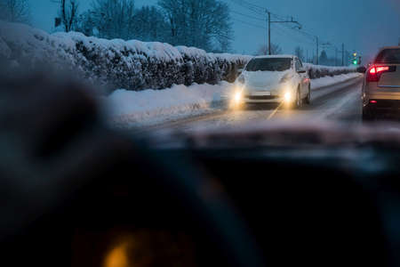 Early morning commute in a snowy conditions from a driver perspective. Snowy morning as seen behind the driving wheel on a daily commute.の写真素材